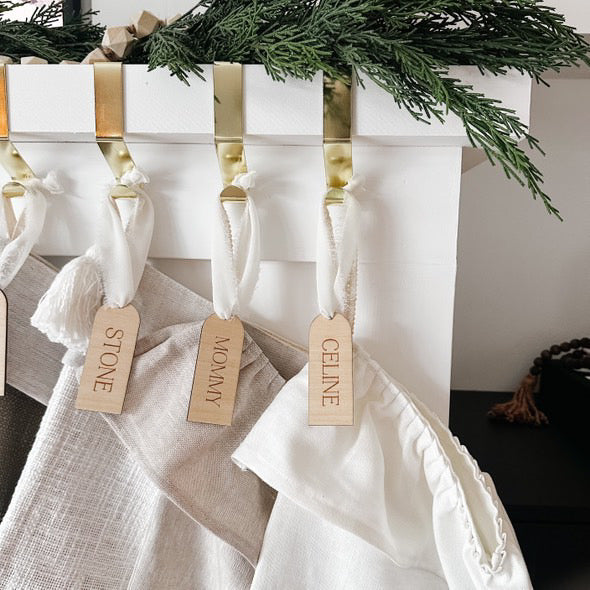 custom wooden christmas tag hanging on stockings above fireplace